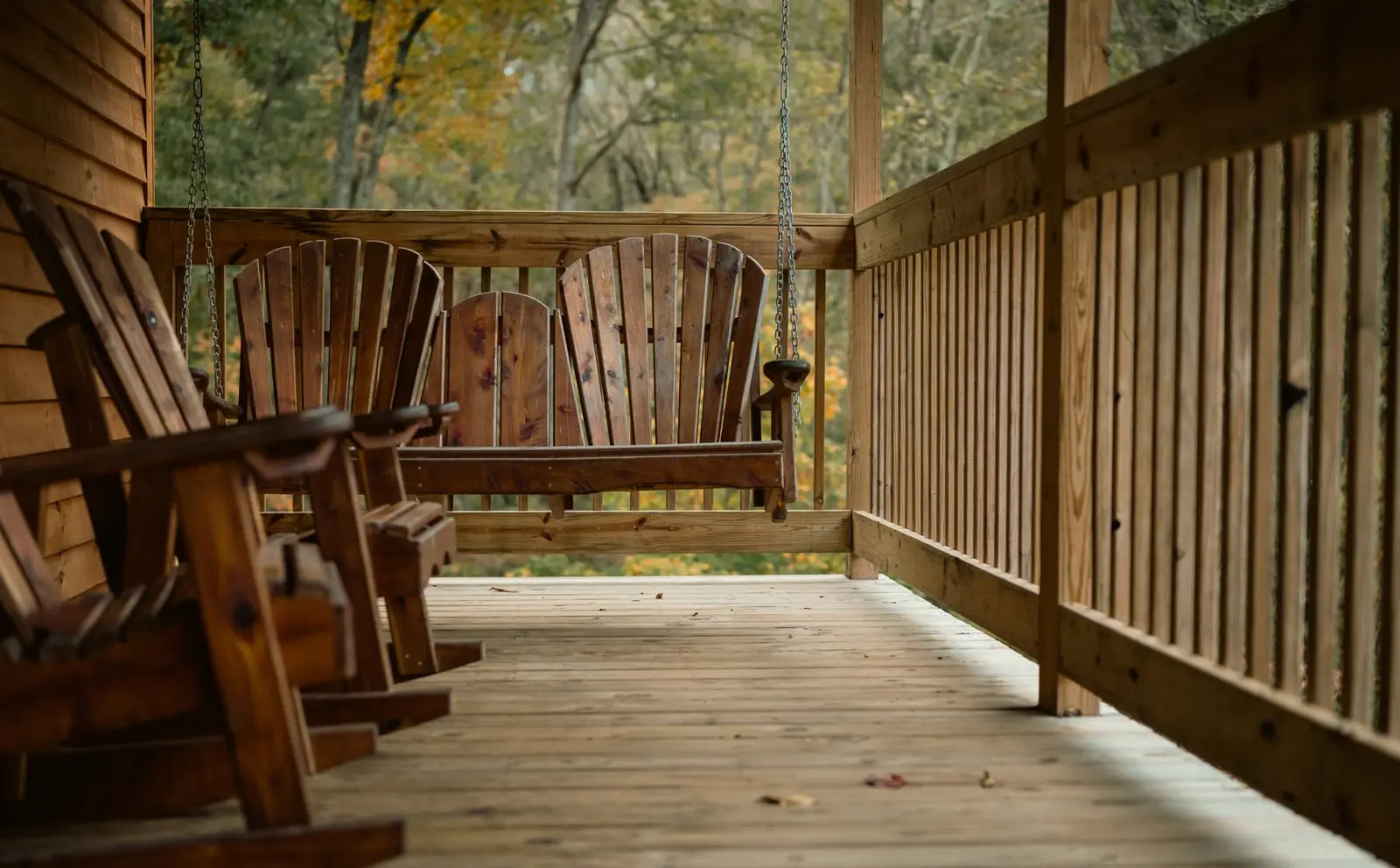 Wooden rocking chairs on a quiet porch surrounded by autumn trees