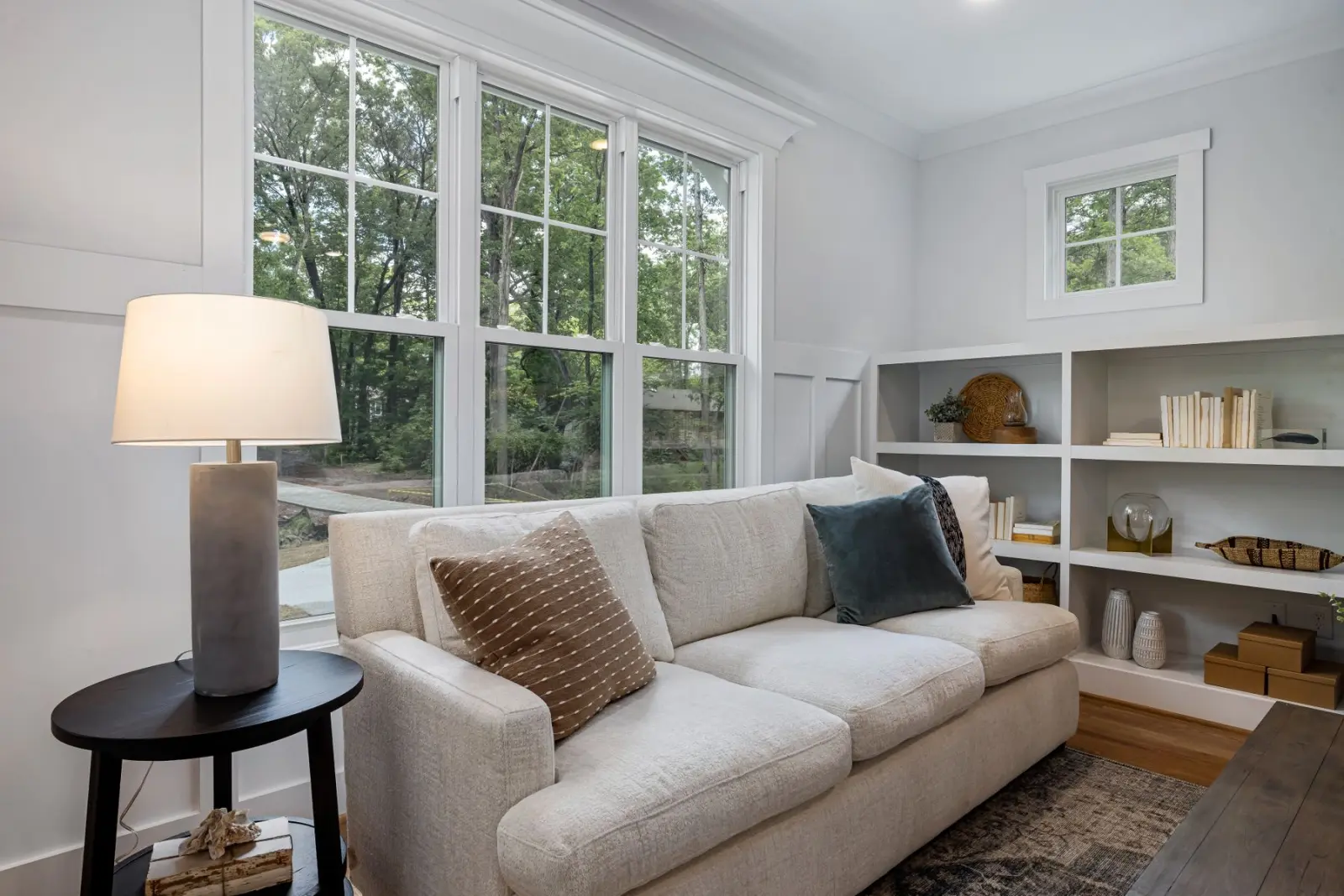 A bright, comfortable living room with a sofa, reading lamp, and bookshelves